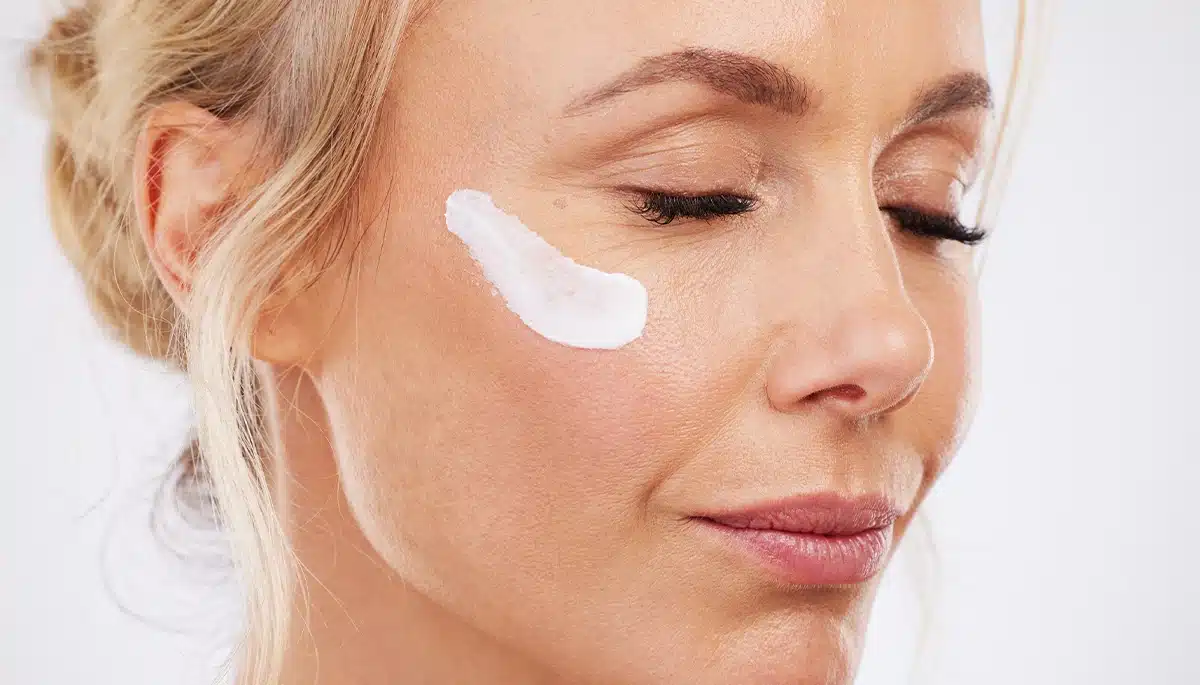 Migliore crema viso per la pelle molto secca applicata sulla guancia di una giovane donna