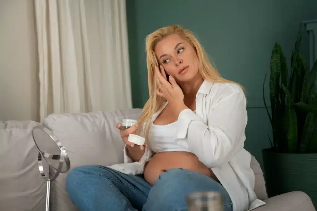 Donna incinta che applica crema viso